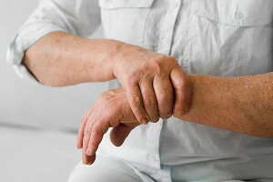 Close-up of an older man gripping his painful wrist with his other hand, highlighting joint pain.