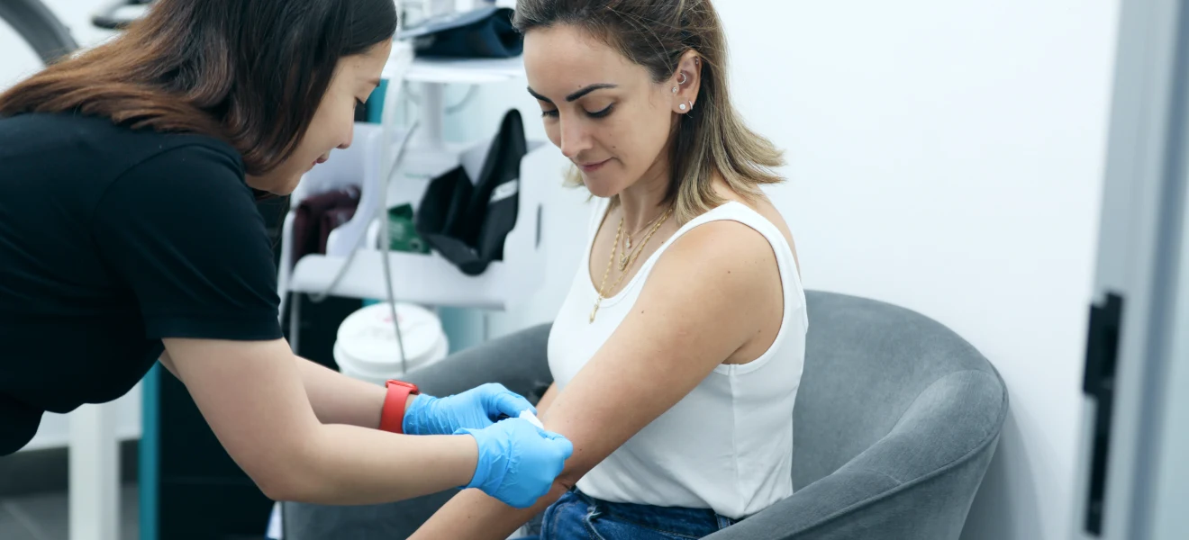 Healthcare professional administering an injection to a woman seated in a clinic, focusing on her arm.
