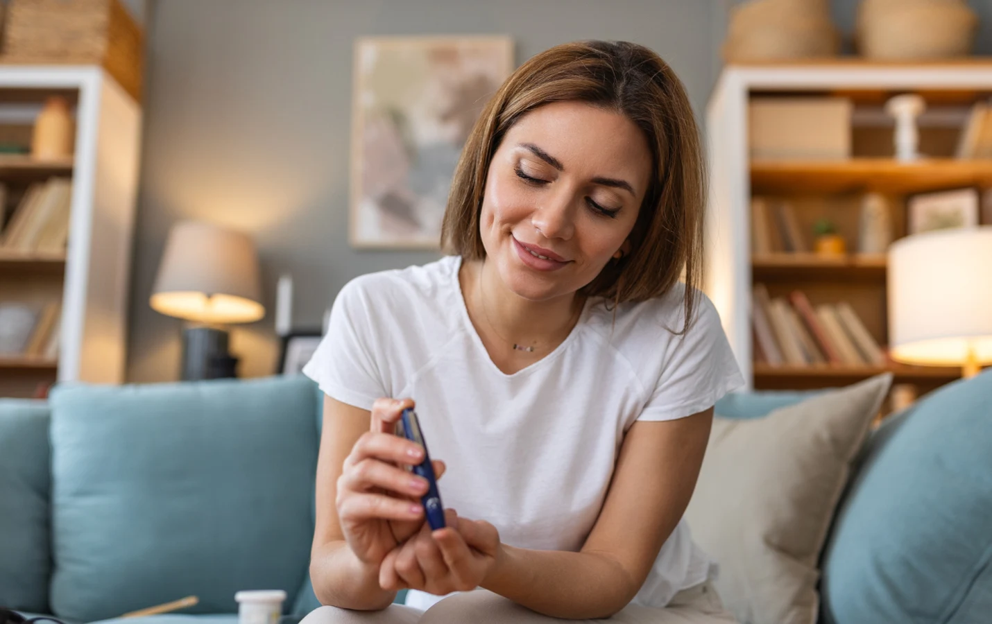 Smiling woman sitting on a sofa at home preparing a medical injection pen